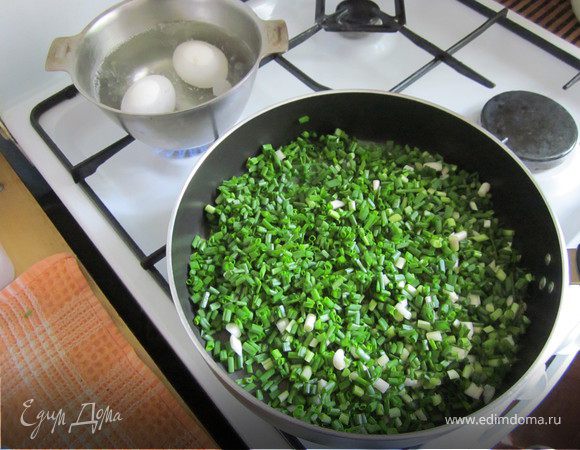 Лук промыть и нарезать. Лука должно быть много, целая сковорода. Слегка прогреть его с маслом, чтобы он размягчился и осел. Посолить, поперчить, добавить нарезанные кубиками отварные яйца.