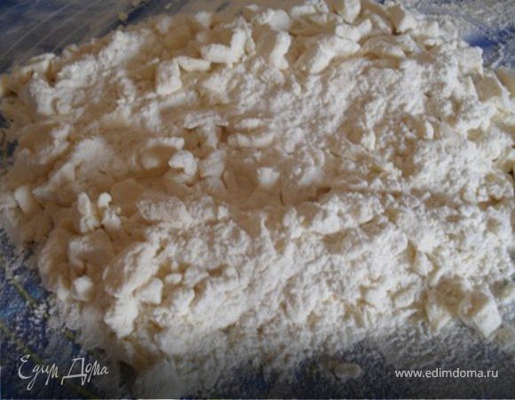 На рабочую поверхность просеять горкой муку, сверху кубики  маргарина, порубить смесь в крошку.
