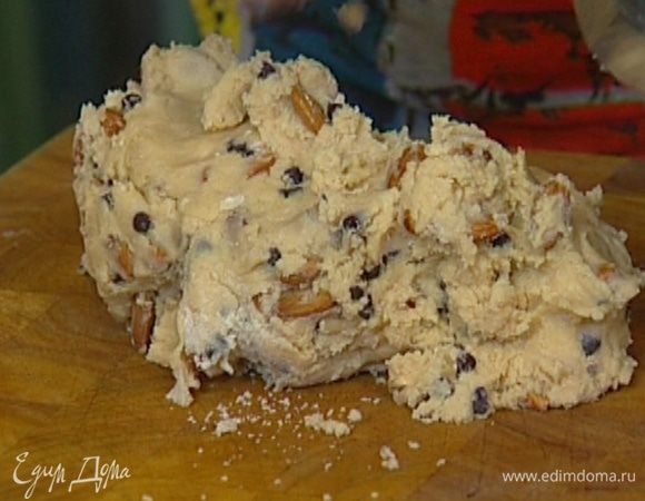 Не выключая комбайна, влить растопленное сливочное масло, добавить муку с разрыхлителем, целые орехи, ванильный экстракт, шоколадные капли и вымешать все еще немного — тесто должно получиться довольно крутым.