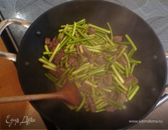 В большой сковороде вок разогрейте соевое масло. Даже если вы не любите жарить на соевом масле, в данном случае оно придется как нельзя кстати и только улучшит вкус блюда! На разогретом масле в течение 3–5 минут обжарьте мясо. Затем добавьте побеги и готовьте еще примерно 2–3 минуты. Чеснок должен «схватиться» и начать источать свежий аромат.
