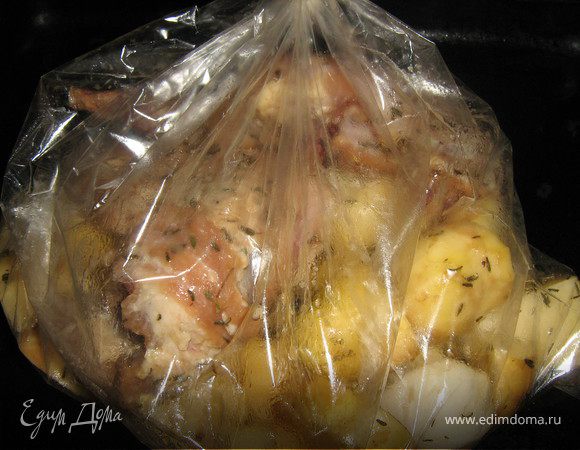 Положите в пакет для запекания, туда же отправьте картофель и лук, залейте все оставшимся маринадом, плотно завяжите пакет и отправьте в духовку на 45–50 минут при температуре 180–200°C.