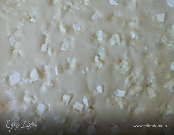 Взять кусочки феты и разложить их по поверхности,слегка утапливая в тесто