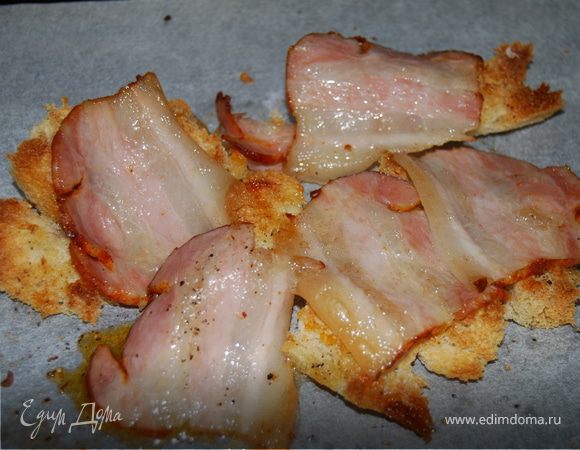 После этого прямо на кусочки хлеба выкладываем грудинку и снова отправляем в духовку минут на 7-8, чтобы она немножко выжарилась и подрумянилась.
Параллельно кипятим подсоленную воду и вбиваем в нее два яйца, чтобы приготовить яйца - пашот. В кипятке они у меня плавали минуты 4, этого вполне хватило, чтоб желтки остались жидковатыми.