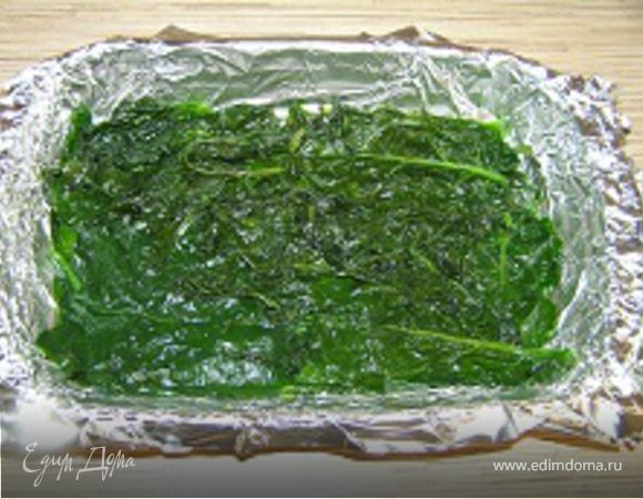 Форму для выпечки застелить фольгой, выложить половину листьев шпината.