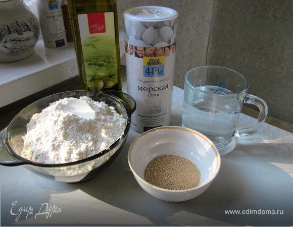 Приготовить тесто: Муку просеять в миску, добавить соль, дрожжи, оливковое масло и воду. Месить 15 минут, хорошо отбивая об стол. Тесто должно стать эластичным и гладким. Можно использовать кухонный комбайн, в этом случае достаточно вымешивать 5 минут.
Скатать тесто в шар, накрыть полотенцем и оставить подходить на два часа в холодильник.
