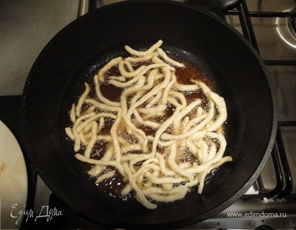 Масло распустить в казане, хорошо нагреть его (перекалить), затем обжарить в нем полученное измельченное тесто, используя при этом сетку, чтобы одновременно вынимать чак-чак и не давать тесту обжариваться сильнее, чем до светло-желтого цвета. Обжаренный чак-чак высыпать на решето или в большое сито, дать стечь лишнему маслу и остудить.
