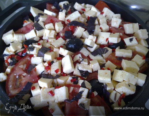 Помидоры нарезать кольцами и разделить на четыре части. Фету нарезать кубиками, чеснок, перчик чили и базилик мелко нарубить. Все смешать, выложить в форму для запекания.