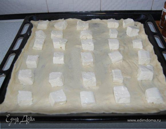 Форму для выпечки (30Х40) смазать маслом. Выложить одну половину теста. Сверху выложить нарезанный кусочками сыр.