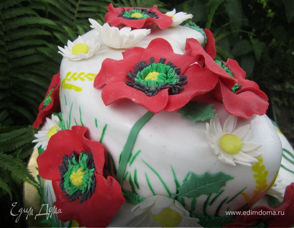 Зарание сделать цветы(маки - http://www.edimdoma.ru/recipes/24500 и ромашки - http://www.edimdoma.ru/recipes/22007).
Из зеленой мастики вырезать листики.
Украсить торт цветами и листиками.
Цветы можно крепить на белый шоколад или разведенный желатин.
