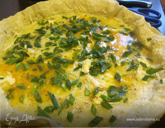 Последний лист также хорошо прижать, края лаваша обрезать ножницами, смазать вверх сметаной, посыпать сыром, разбить яйца, слегка разболтав яйца, поперчить и присыпать зеленым луком. Выпекать в духовке 200 гр под грилем 5-7 минут.