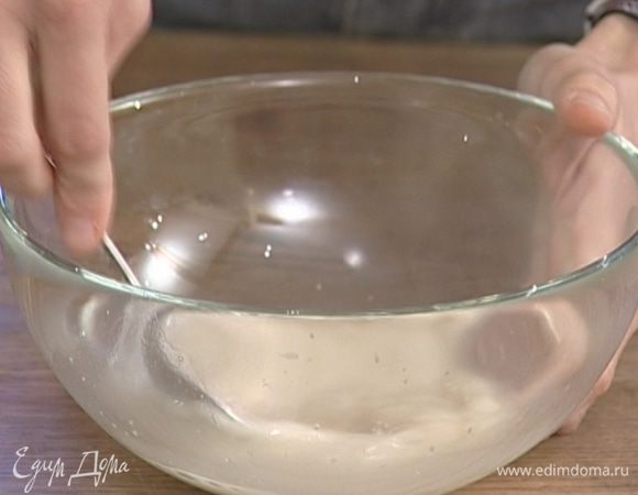 В большую подогретую миску влить 150 мл теплой воды, всыпать дрожжи и сахар.