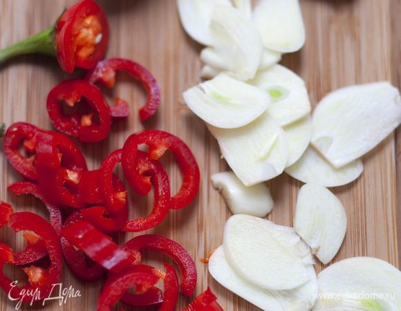 Чеснок тоже почистить и нарезать пластинками. Перец чили, удалив семена, порезать кольцами.