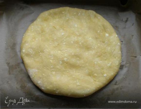 Тесто разделить  на две части, одна немного больше другой. Скатаем каждую часть в шар, затем на посыпанном мукой столе ( у меня доска большая)  раскатаем каждый шар в круг (большего и меньшего диаметра).
Круг поменьше выкладываем на застеленный пергаментом противень, смазываем края водой и распределяем по нему сырную начинку. Накрываем вторым кругом. Загибаем края верхнего круга под нижний круг и защипываем. 