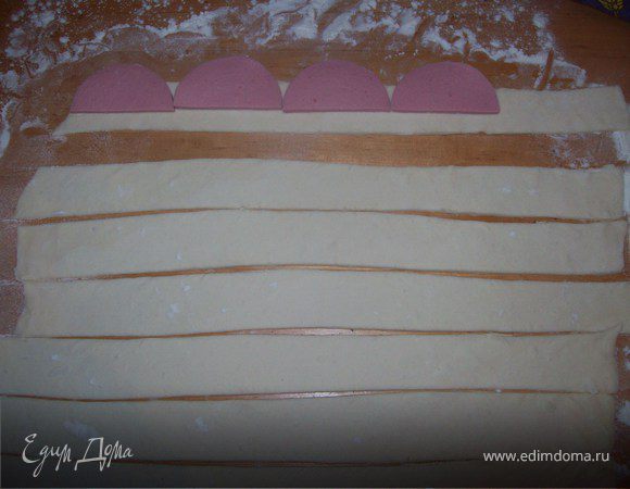 Колбасу нарезать ТОНЮЮЮСЕНЬКИМИ ломтиками и выложить на полоску теста, так чтобы остался небольшой хвостик, свернуть розочку, хвостик теста смочить водой, чтобы лучше проклеился шов, и выложить на противень, застеленный бумагой.