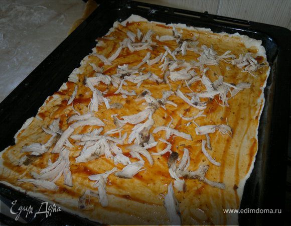 куриную грудку руками разделываем на мелкие кусочки и выкладываем на смазанное кетчупом тесто