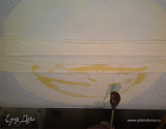 Растопить сливочное масло на огне и смазать тесто равномерно его распределив. 