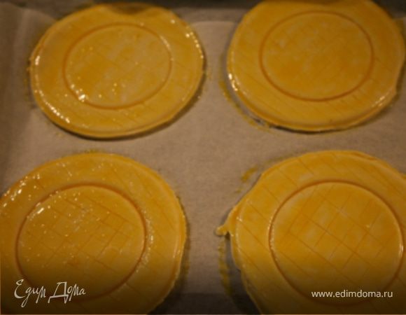Тесто нарезать на квадраты,из каждого мисочкой вырезать круг диаметром 12-13 см.Внутри каждого круга круглой формочкой или стаканом диаметром 7-8 см продавить тесто,но не прорезая его до конца.Желтки взбить с солью,куркумой и 1 ст. л . воды.Уложить круги теста на противень,застеленный пергаментом,смазать желтком.Легко надсечь каждый круг ножом крест-накрест и поставить в разогретую до 190С духовку,выпекать до золотистого цвета,10 мин.