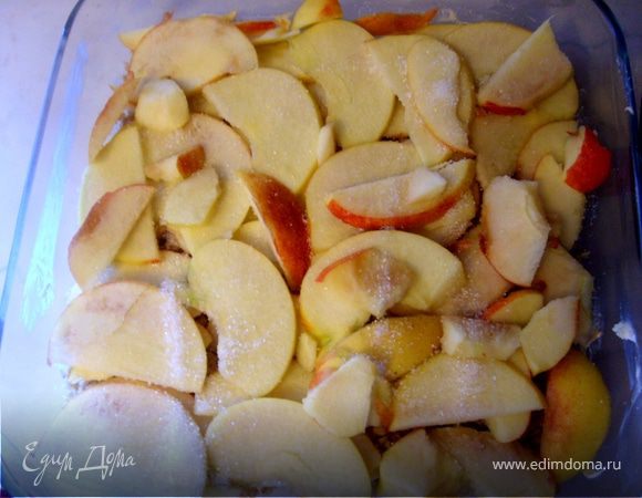 Форму смазать маслом, выложить половину обжаренных хлопьев, уложить сверху - яблоки, посыпать сахаром и накрыть оставшимися хлопьями.