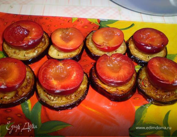 Теперь на блюдо, на котором будем подавать закуску, выкладываем кружочки баклажанов, сверху ложим половинку сливы