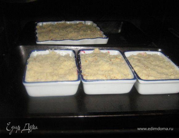 Форму смазать маслом. Выложить сливы, затем крошку. Выпекать на среднем огне около полу часа.