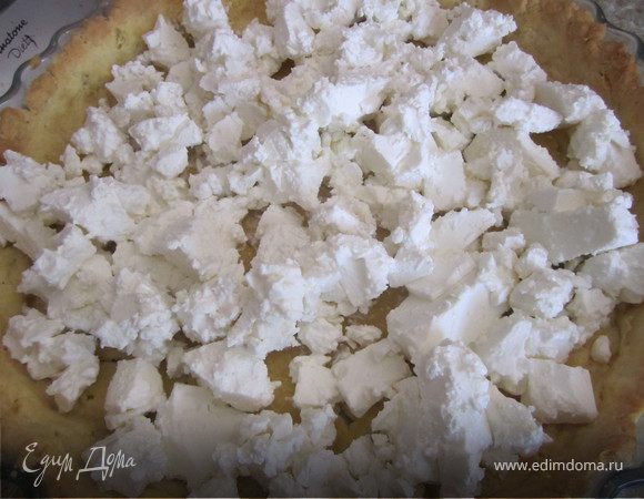 Достать форму с тестом из духовки.
Убрать пергамент с крупой.
Выложить порезанную фету.