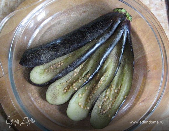 В то время как начинка на сковороде доходит до готовности, промоем и отожмем баклажан. Разложим его веером на тарелке пригодной для микровоки (в моем случае - крышка от кастрюльки), присолим и поперчим. Если соберетесь готовить больше одной порции, то раскладывайте баклажаны прямо на протвень без всякого масла.
