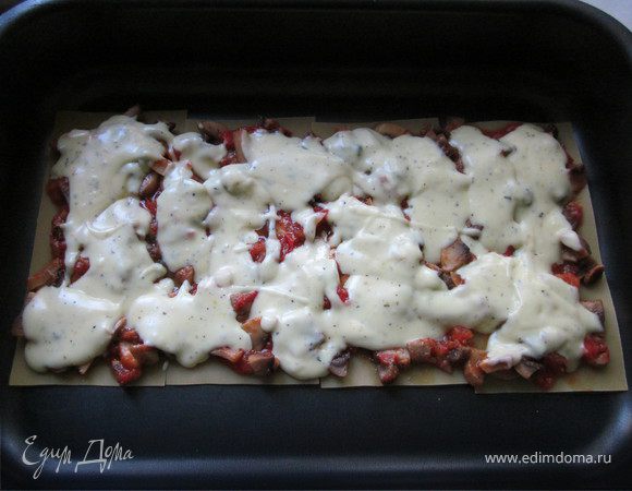 Начинаем собирать лазанью. Выложить в форму 4 листа лазаньи, положить слой грибов с томатами (1/2 часть), полить 1/3 соуса. 