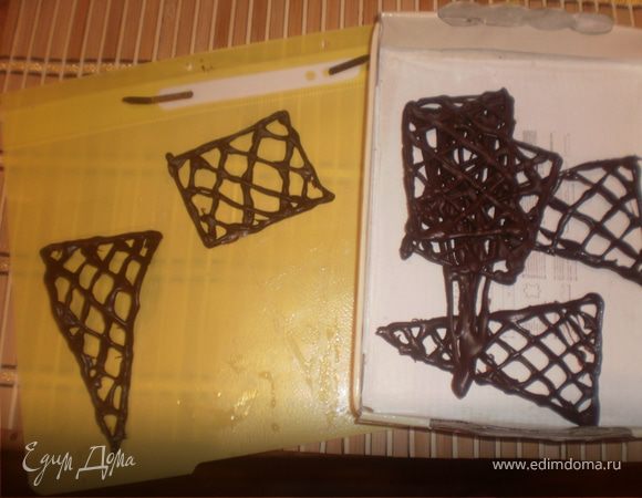 Растапливаем шоколад на водяной бане. Из мешка с тонкой насадкой на файлик отсаживаем нужные нам фигуры (прямоугольники, треугольники, фигурки для банта, заполненные решеточкой).
