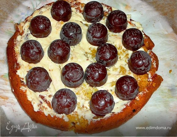 Бисквит достать,остудить разрезать на пополам,на два одинаковых коржа:).Если бисквит суховат(хотя это наврдли будет,можно пропитать его слегка ликером).Смазать первый корж небольшим кол-вом крема.Очень удобно работать силиконовой лопаткой.Достать конфеты и выставить на крем,по кругу конфеты.