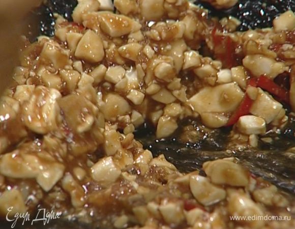 В оставшемся в воке масле обжарить чили, чеснок и имбирь, добавить орехи, измельченную зелень, соевый и рыбный соус, сахар и сок лайма.