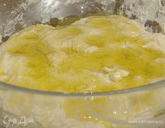 Влить 25 мл оливкового масла и еще раз вымесить. Затянуть миску пищевой пленкой и оставить на 45 минут.