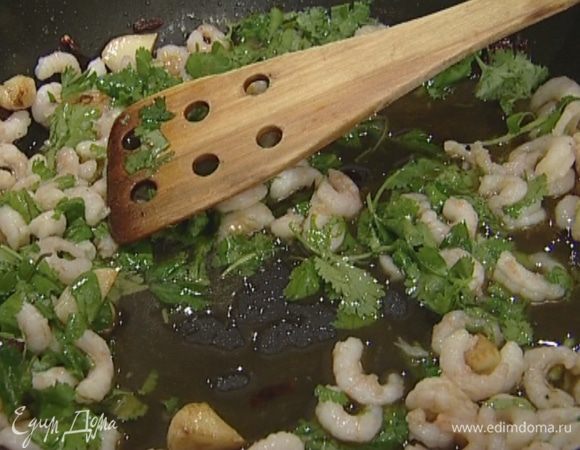 Добавить креветки и половину листьев кинзы, перемешать и жарить не дольше одной минуты.