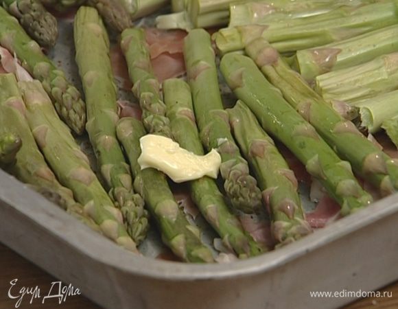 Выложить на противень слой нарезанной ветчины, сверху уложить спаржу, а на спаржу — кусочки сливочного масла.
