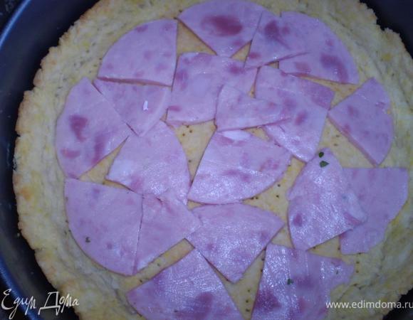 На полуготовый корж раскладываем тонкие ломтики ветчины 