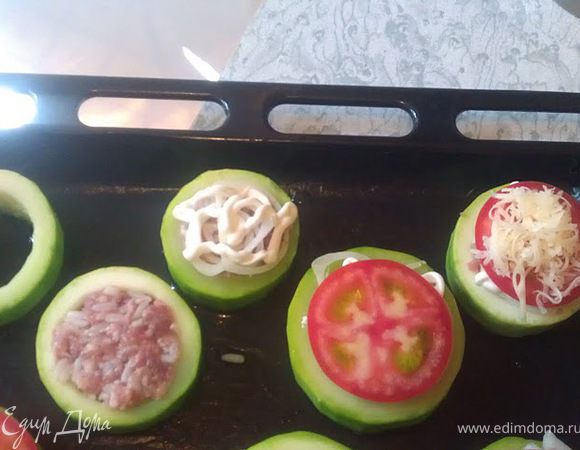 Выкладываем фарш в отверстия. Сверху несколько луковых колечек , немного майонеза, кружок помидора, натертый сыр. 