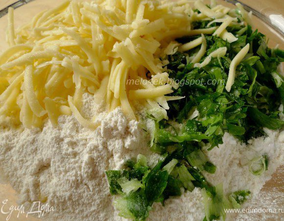 Муку соединяем с разрыхлителем и содой. Сыр натираем на крупной терке. Зелень мелко рубим. Добавляем к муке сыр, зелень и хорошо все перемешиваем.