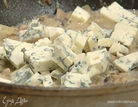 Приготовить начинку: растопить в сковороде 1 ст. ложку сливочного масла и обжарить лук и чеснок до золотистого цвета, выложить в сковороду грибы, поперчить, посыпать солью с тмином и, помешивая, обжаривать пару минут, затем влить портвейн, увеличить огонь и дать алкоголю выпариться. Добавить 1 ст. ложку сливок и голубой сыр, перемешать и тушить несколько минут на медленном огне, чтобы ушла лишняя жидкость.