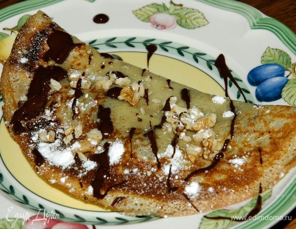 Смазать блины шоколадом, свернуть их, посыпать орехами и сахарной пудрой. 