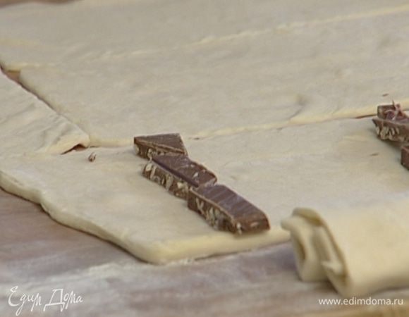 Завернуть кусочки шоколада в тесто и уложить на противень.