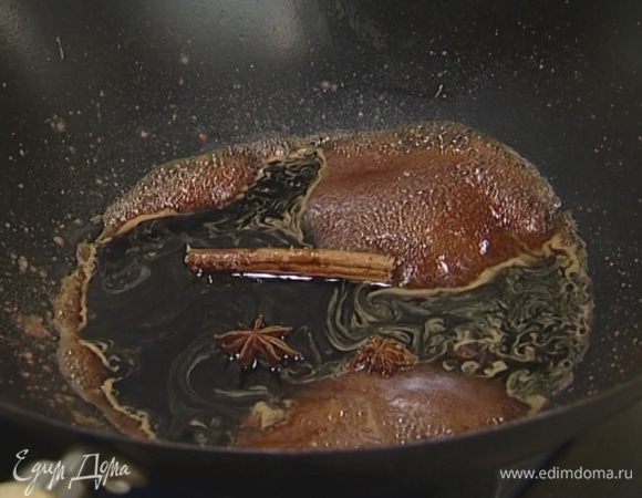 В разогретую сковороду вок отправить палочку корицы, влить соевый соус и вино, добавить бадьян, коричневый сахар, кунжутное масло и натертый имбирь.