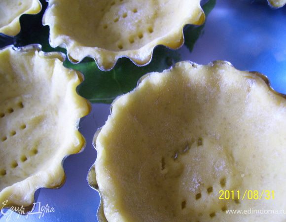 Охлажденное тесто раскатать в тонкий пласт ( прим. 2 мм.). Вырезать кружки и уложить их в формочки (у меня формочки диаметром 8 см, вырезала кружочки диаметром 10 см. "Село" идеально). Дно наколоть вилкой. Теста хватает ровно на 8 корзиночек.