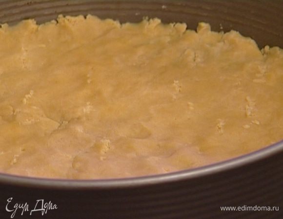 Разъемную форму смазать маслом, выложить тонким слоем тесто. Проткнуть его в нескольких местах вилкой, накрыть бумагой для выпечки, высыпать на бумагу около килограмма гороха (или любой крупы). 