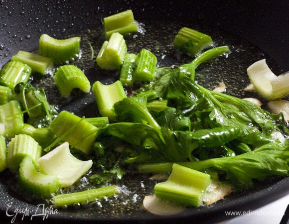 В большой и глубокой сковороде разогреть оливковое масло и слегка обжарить сельдерей, чеснок и несколько веточек петрушки. Влить вино и прогревать на небольшом огне.