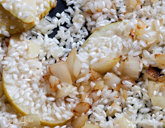 Всыпать рис, перемешать, чтобы он пропитался ароматами лука и груши, влить вино, а затем на сильном огне его выпарить.