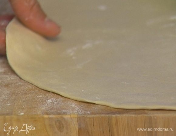 Присыпать рабочую поверхность мукой, раскатать тесто как можно тоньше и вырезать из него небольшие кружки.