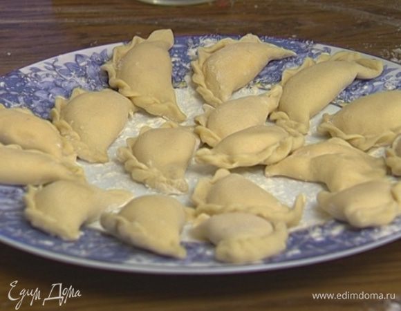 Сформировать вареники, положив на тесто немного начинки, смазать края водой, слепить и защипнуть.