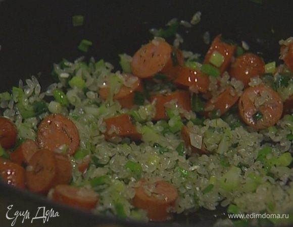 Добавить нарезанные колбаски, всыпать рис, все перемешать.