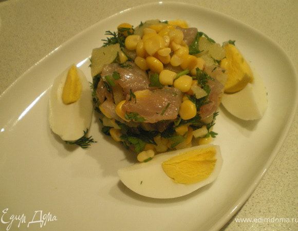 Рыбу отделить от костей, нарезать кубиками. Картофель также нарезать кубиками. Зелень измельчить. Добавить кукурузу. Посолить. Выложить салат, сбрызнуть оливковым маслом и украсить дольками яйца и горстью кукурузы.