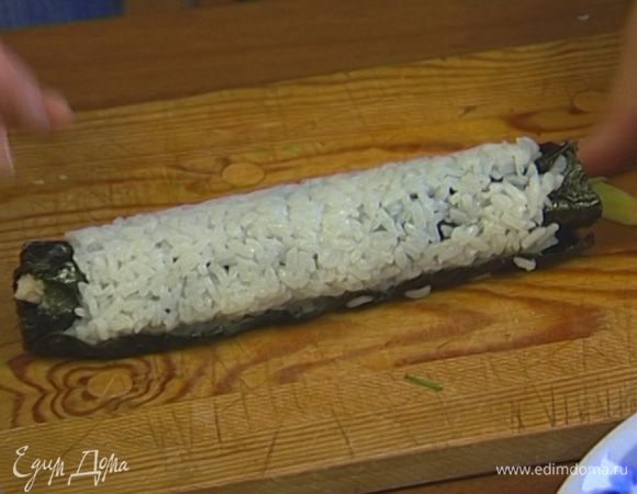 Свернуть коврик, удерживая начинку рукой. Сформировать ролл, надавив на салфетку. Развернуть салфетку и удалить пленку.