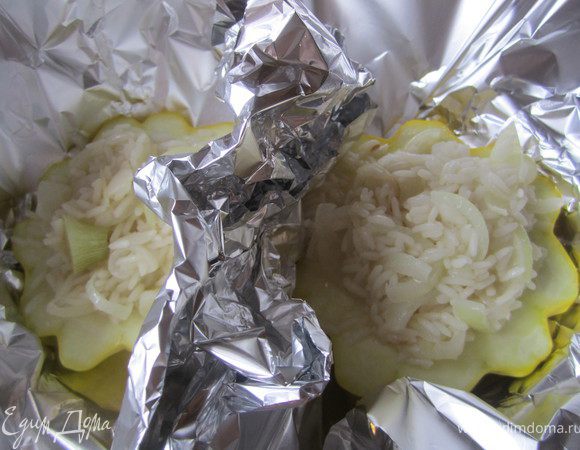 Половинку патиссона положить на фольгу.
Выложить на него часть риса.
Добавить пару ложе воды.
Завернуть плотно фольгу.
Поставить в разогретую (180 гр) духовку на 15-20 минут.